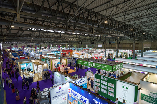 An indoor exhibition hall is full of vendors.