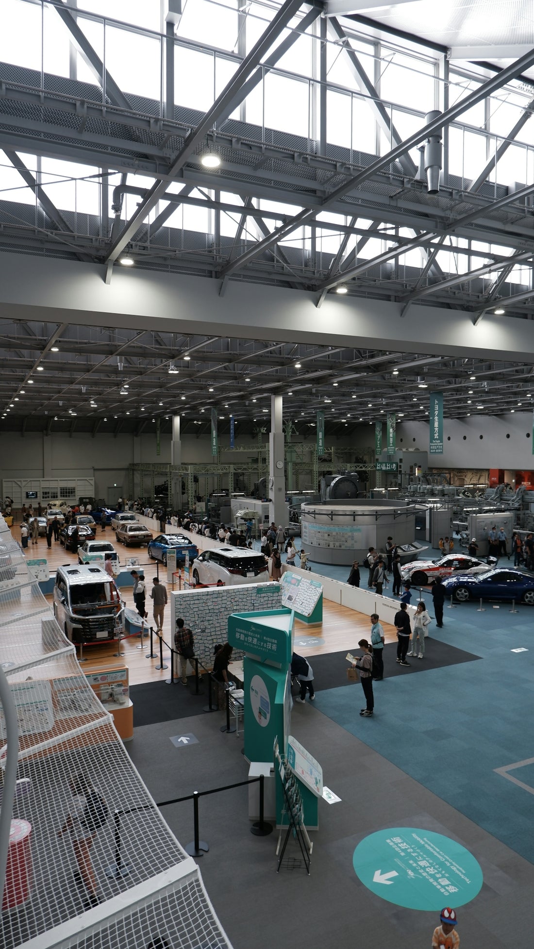 Cars displayed at an indoor exhibition hall with visitors