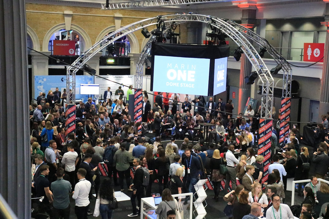 Crowd gathered at an indoor event with a large screen.