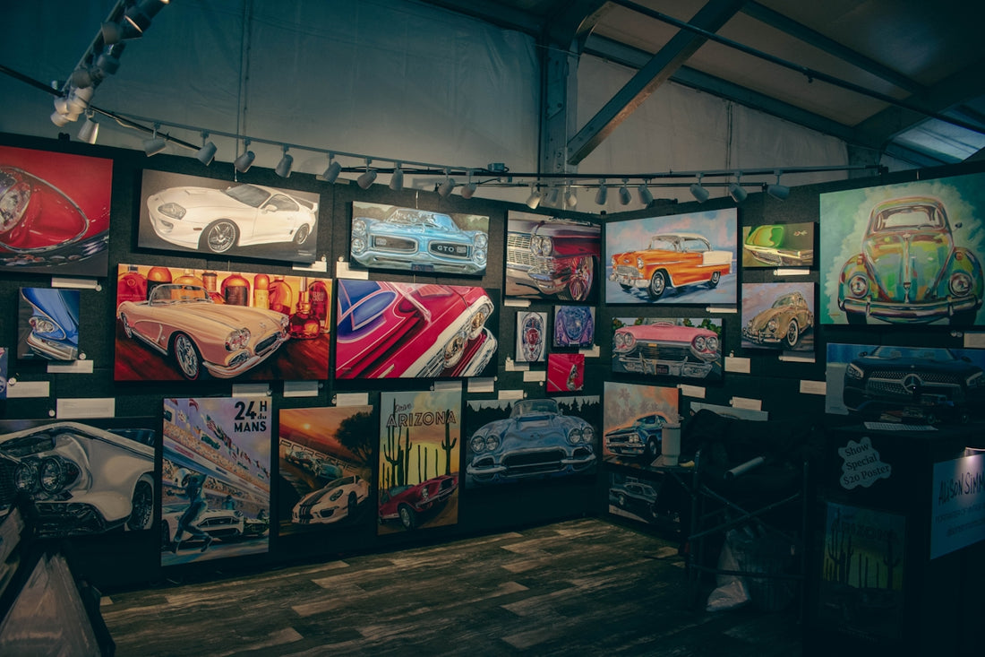 Collection of car art displayed on a wall.