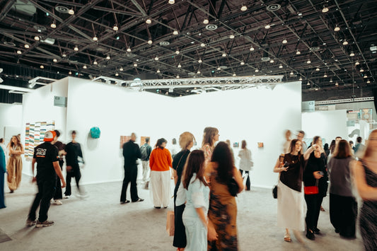 People browse art exhibits in a large, well-lit gallery.