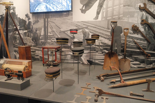 Historical museum exhibit displaying old tools, hats, and railroad scenes.