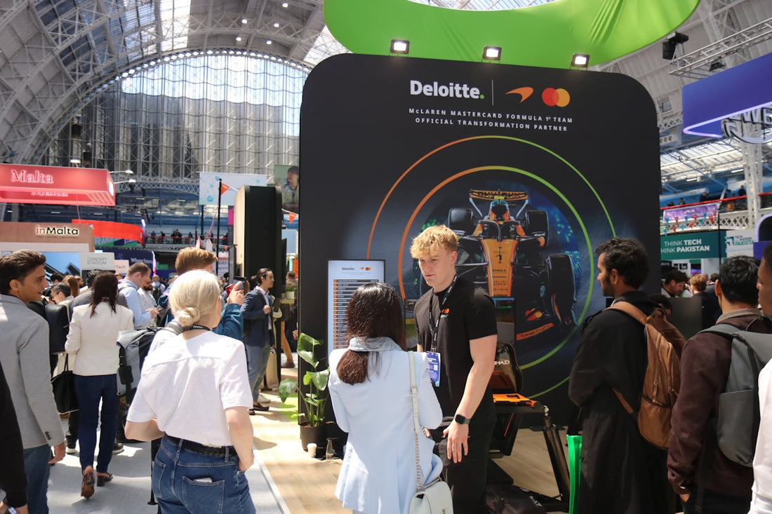 Attendees interact with a deloitte and mastercard exhibition booth.