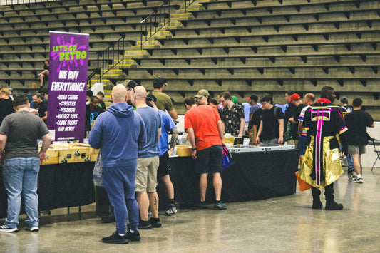 Attendees browsing vendor booths at an indoor convention with bleachers.